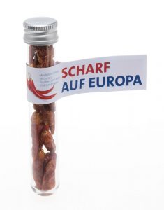 Transparentes Röhrchen mit Chillie - darum eine Banderole mit "Scharf auf Europa"